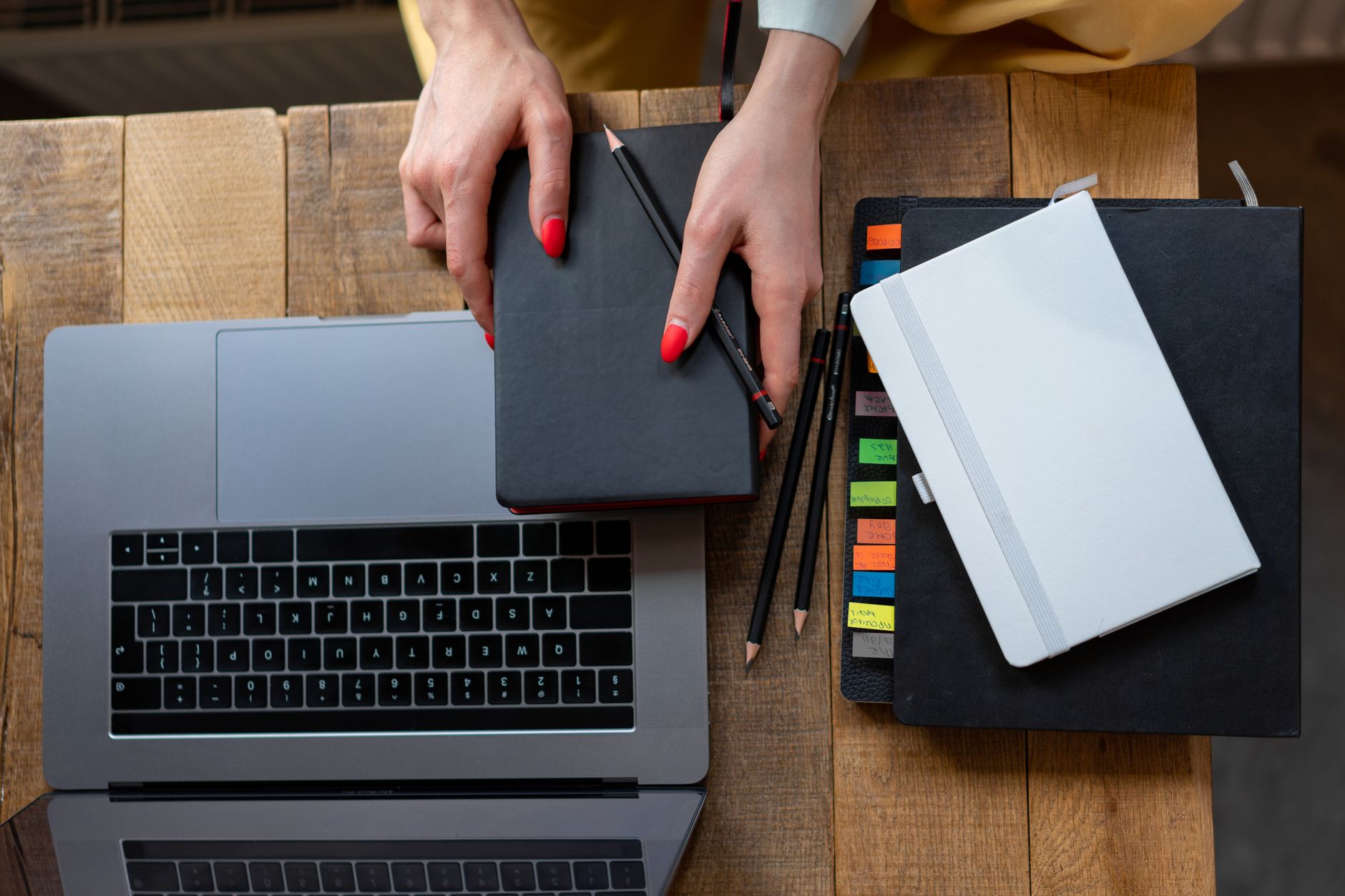 Top-down view of a desk with laptop, planner, and notebooks.
